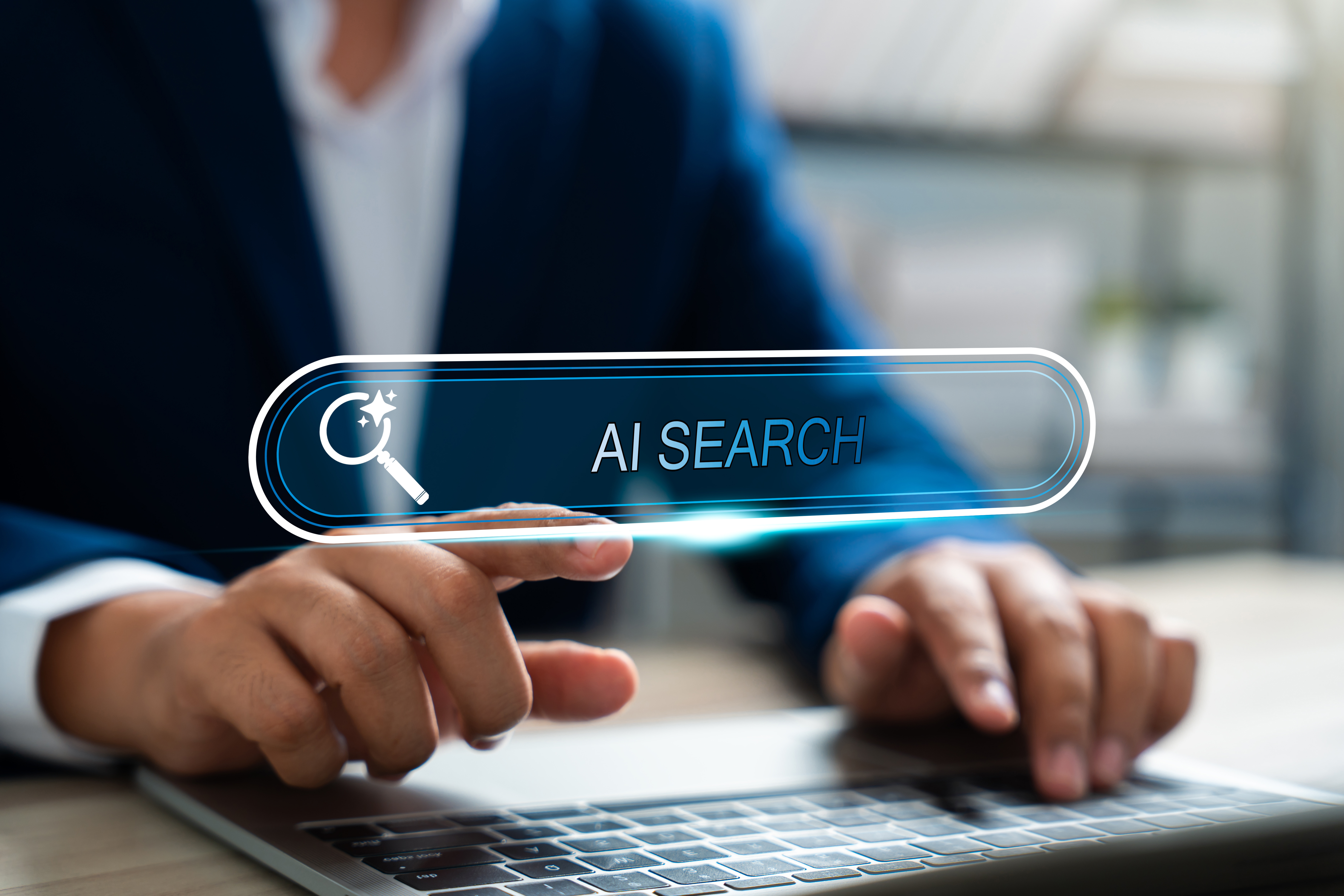 Person in a suit using a laptop with a glowing virtual search bar that reads “AI SEARCH,” symbolizing artificial intelligence-powered search technology and digital innovation.
