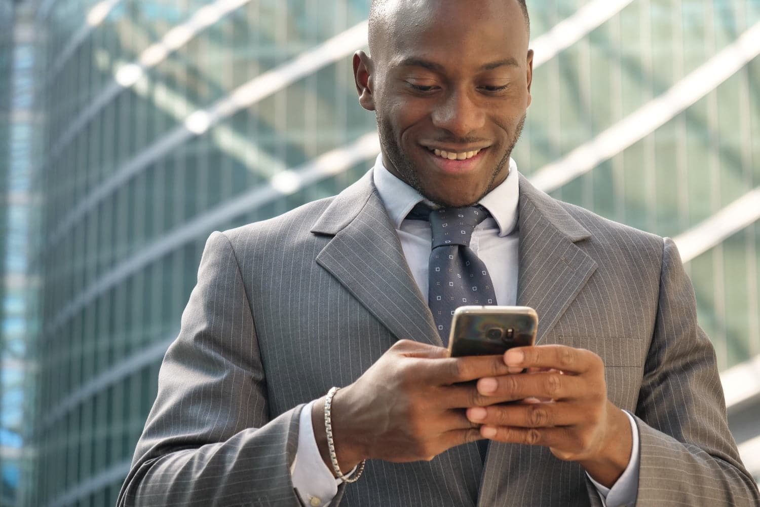 Man standing in a business suit looking at his phone. 